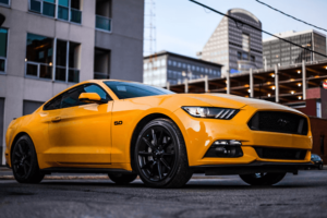 dbafba0e-14b2-11ed-a4fe-62898edc0f74 (1) Burnt Orange Mustang with buildings in the background